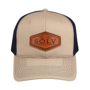 Abu Garcia Sölv Trucker Cap mit beiger Vorderseite und Schirm, marineblauem Netz und Lederpatch mit Sölv-Logo.
